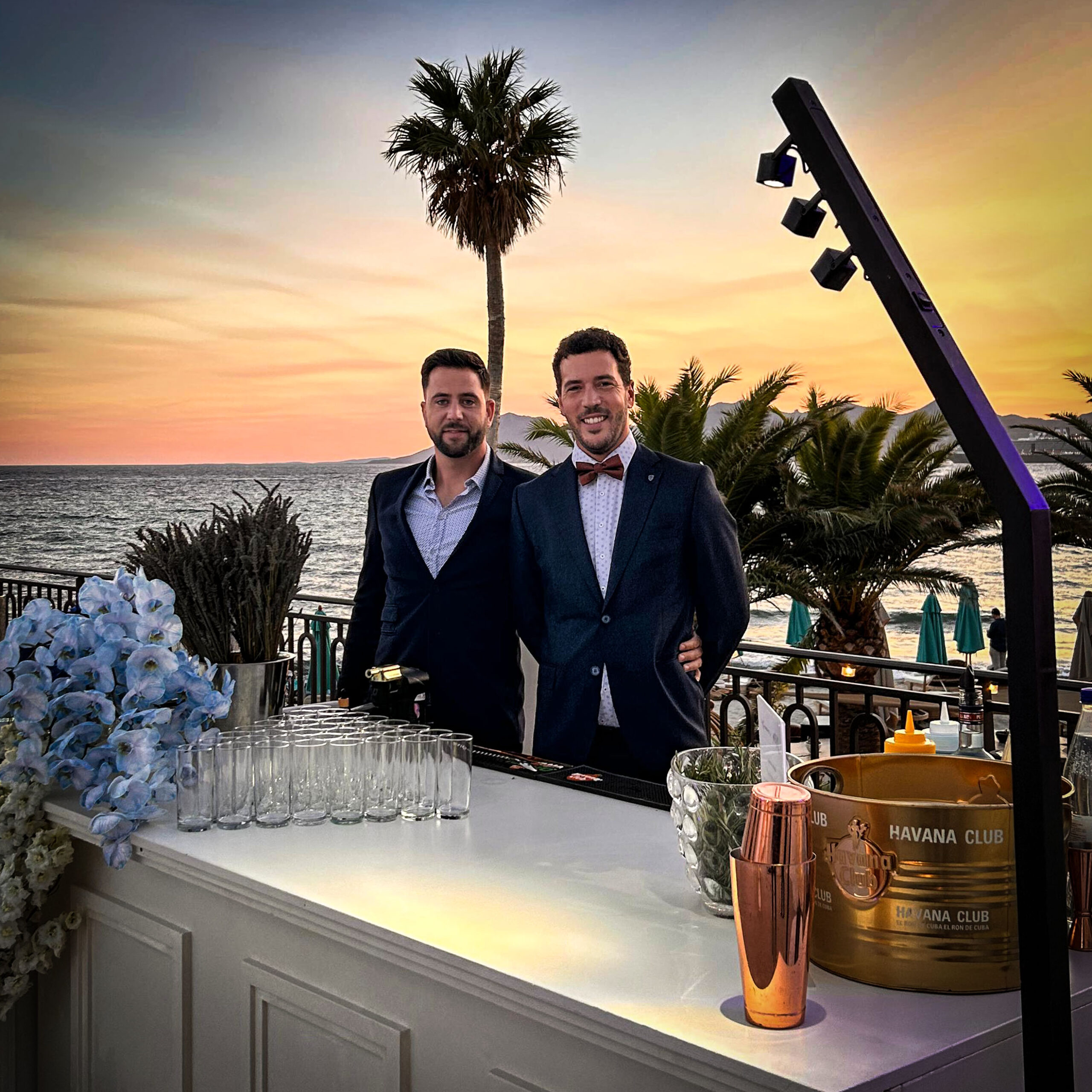 Deux barmans derrière un bar à cocktails au coucher du soleil