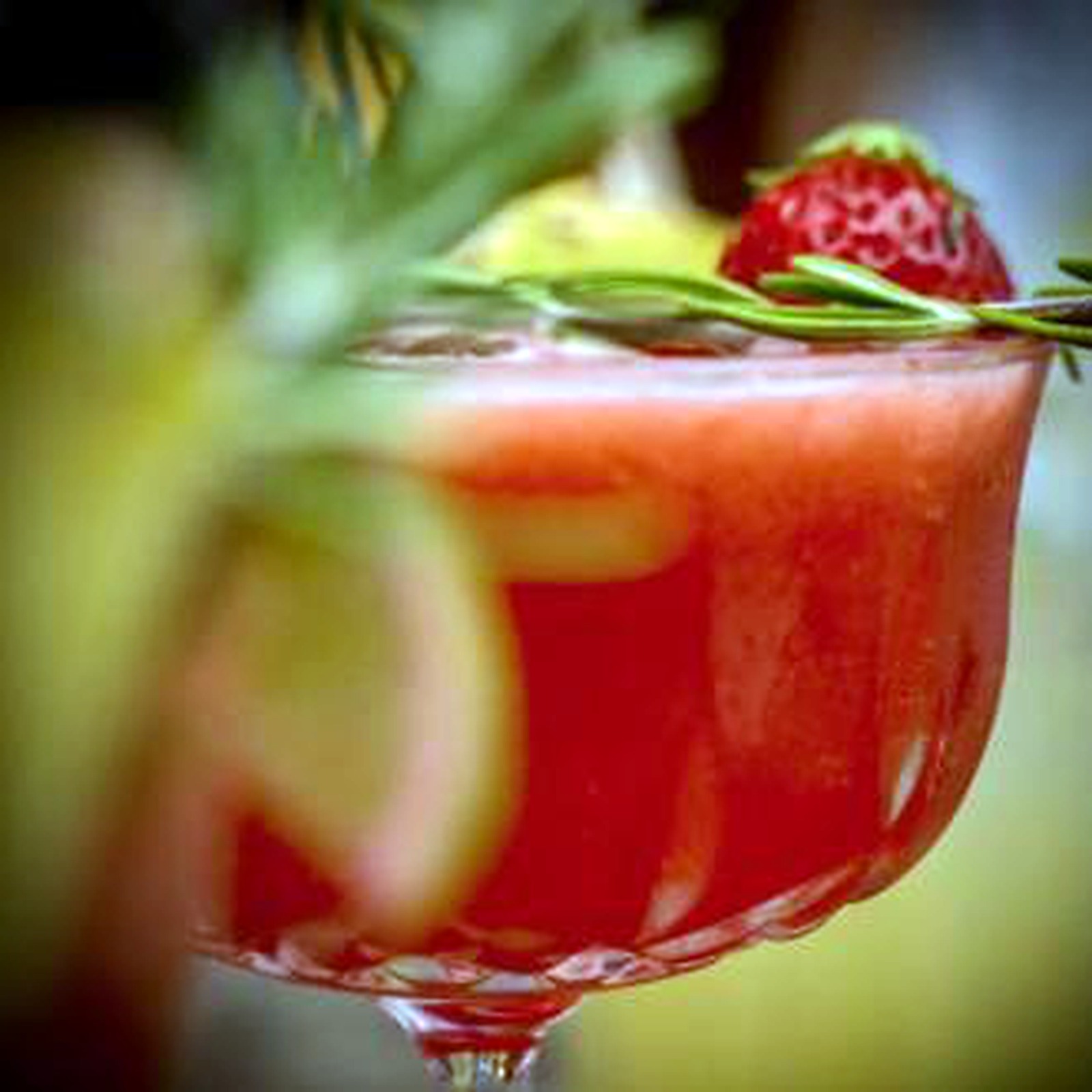 Cocktail rouge décoré de fraise et de romarin