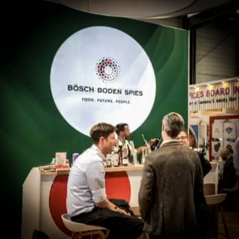 Visiteurs échangeant devant le bar du stand Bösch Boden Spies